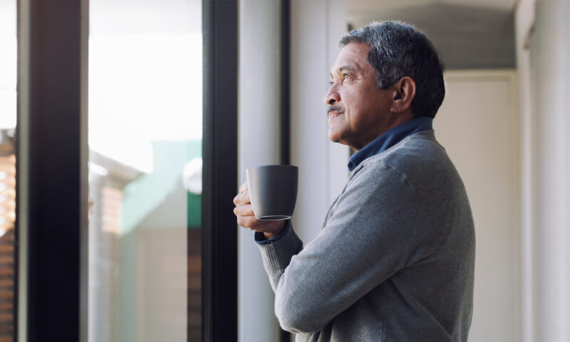 Shot of a senior man drinking coffee and looking thoughtfully out of a window